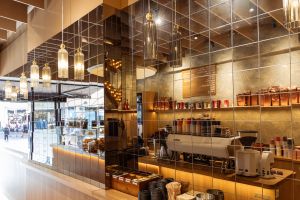 Blick auf eine moderne Kaffeebar mit Espressomaschine, die sich in einer Wand aus quadratischen Spiegelelementen spiegelt.