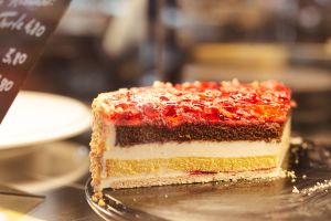 Geschichteter Kuchen mit rotem Fruchtbelag in der Auslage.